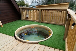 A wooden deck with a hot tub surrounded by artificial grass.