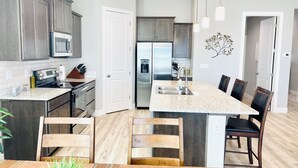 Eine moderne Küche mit Granit-Arbeitsplatten, Edelstahlgeräten und Holzküchenstühlen.