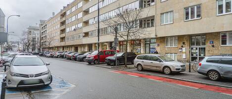 A multi-story residential building with a row of parked cars along the street.
