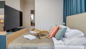 A hotel room with a bed, a TV, a bedside table, a tray with cups, and a window with curtains. - Apartament Wiejska I (Warsaw)