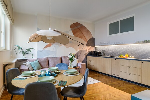 Eine moderne Küche mit Essbereich, Holzschränken und einer großen Wandmalerei mit Blättern.