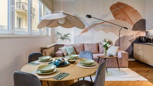 A modern dining area with a round table set for four, a sofa, and a kitchen area in the background. - Apartament Wiejska I (Warsaw)