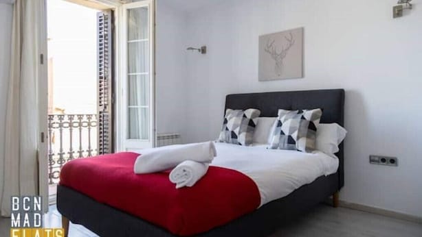 A bedroom with a bed, a red blanket, and a white pillow. - Barcelona - Poble Nou (Barcelona)