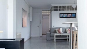 A modern living room with a grey sofa, a white coffee table, and a dining table. There is a door leading to another room, and a framed artwork on the wall. - Barcelona - Poble Nou (Barcelona)