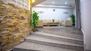 Ein modernes Wohnzimmer mit Steinwand, einer Treppe und einer Sitzecke mit Sofa und Couchtisch.