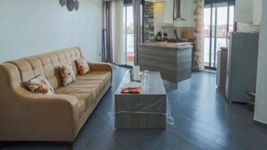 Ein Wohnzimmer mit einer Couch, einem Couchtisch und einer Küchenzeile im Hintergrund.
