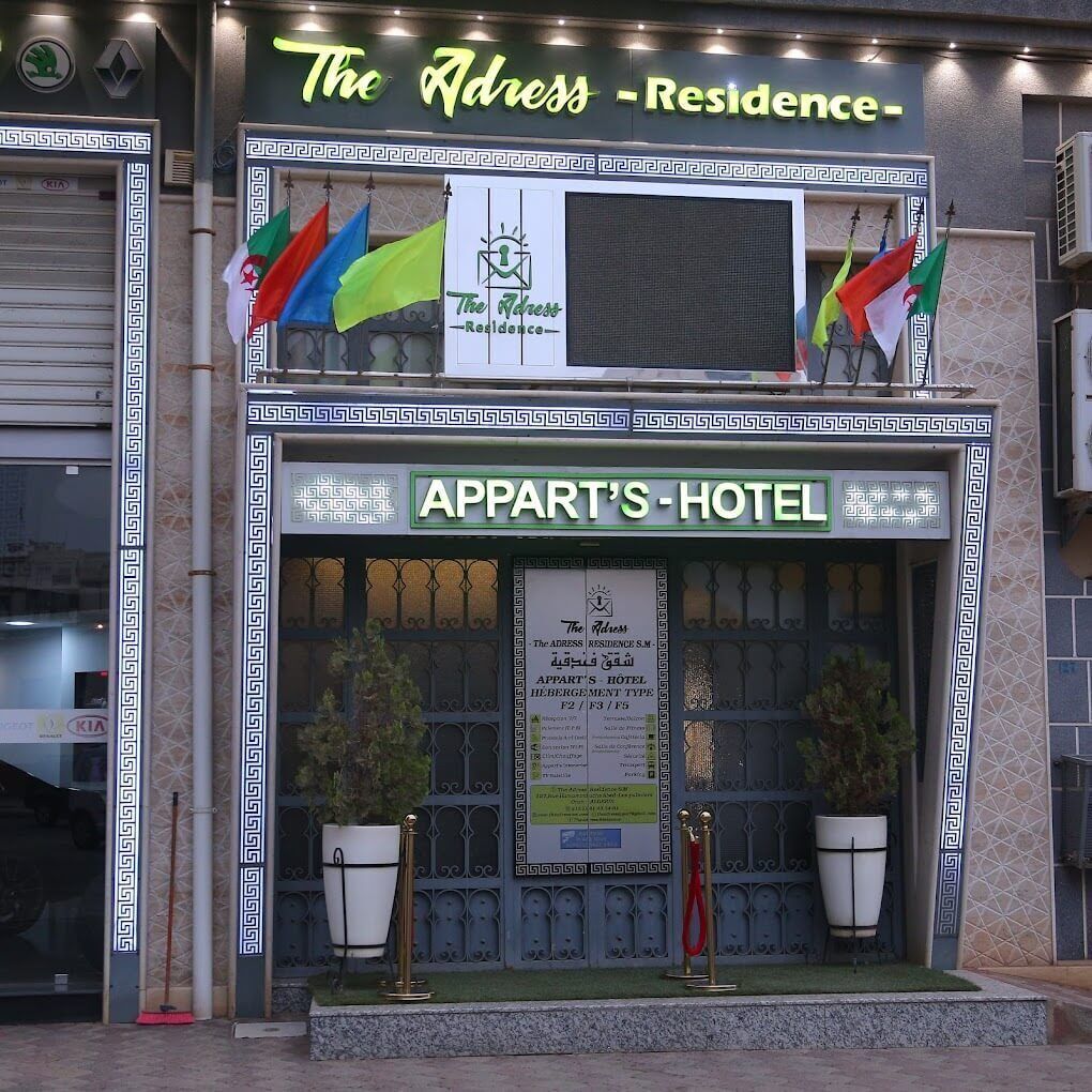 The Address Residence - Appart's Hotel, met een traditionele gevel, vlaggen en een bord.