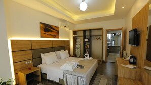 Ein Hotelzimmer mit einem großen Bett, Nachttischen, einem Fernseher und einem durch eine geöffnete Tür einsehbarer Badezimmer.