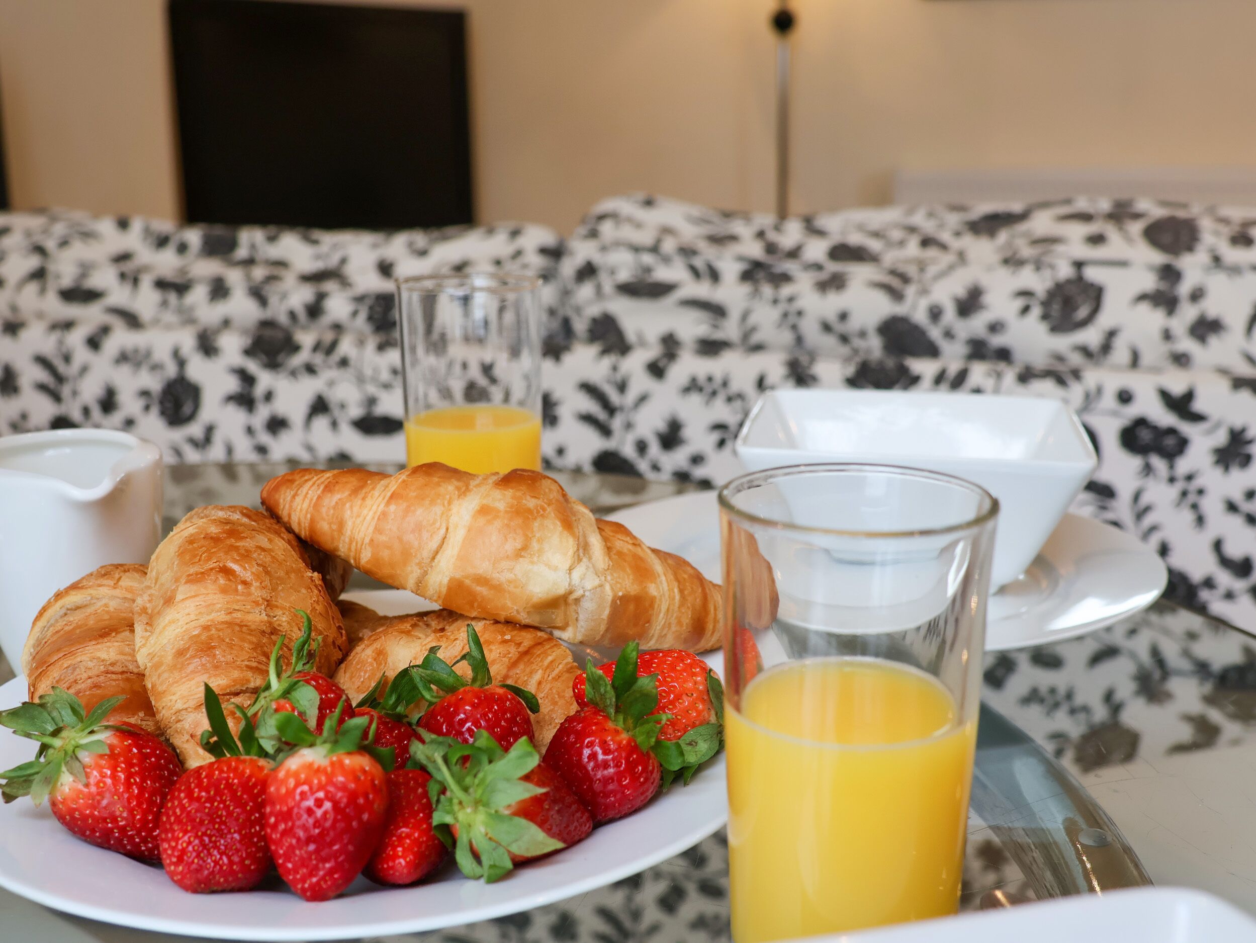 A breakfast setting with croissants, strawberries, and orange juice on a table.