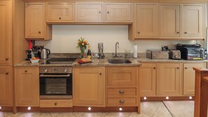 A kitchen with wooden cabinets, a built-in oven, a sink, and various appliances. - Powder Keg (Whitby)