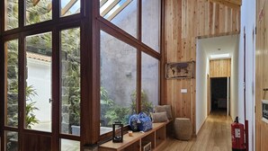 A spacious room with large windows, wooden flooring, a bench with cushions, and a fire extinguisher. - Casa do Cinzeiro, Açores - With private pool! (Açores)