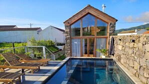 A swimming pool with wooden loungers and a stone wall. - Casa do Cinzeiro, Açores - With private pool! (Açores)