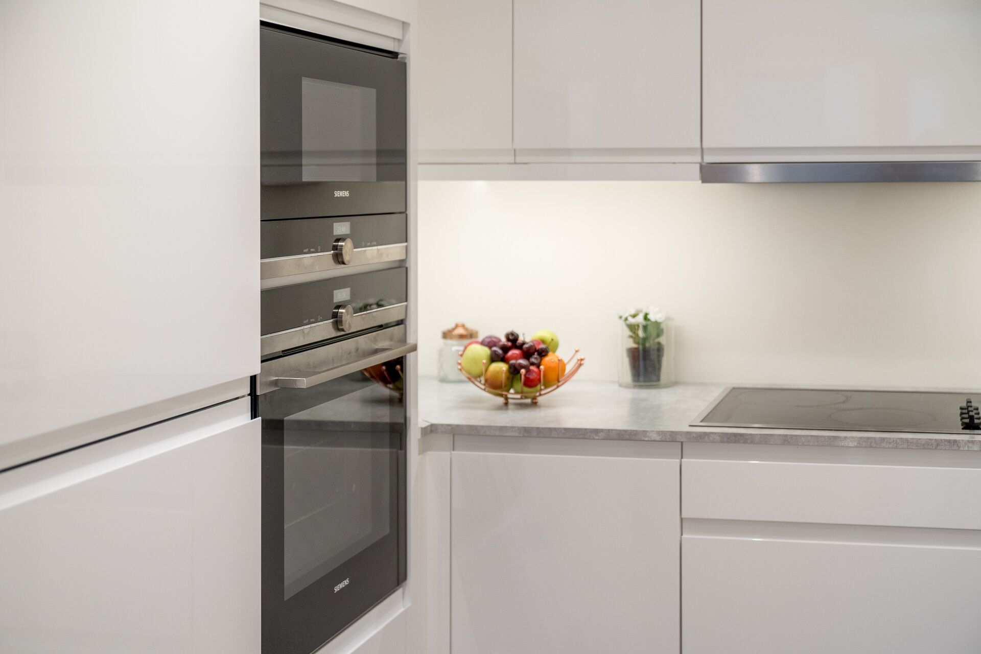 A kitchen with a built-in oven and a fruit bowl on the counter.