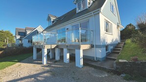 A modern house with a large glass balcony, a steeply pitched roof, and a gravel driveway. - Trebarfoote - Three Bedroom Cottage, Sleeps 6 (Polruan)