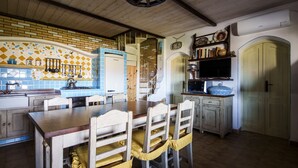 A rustic kitchen with a wooden table, chairs, and a brick backsplash. - Casa Armonia – Terrace & Beach Nearby | Welcomely (Tanaunella)