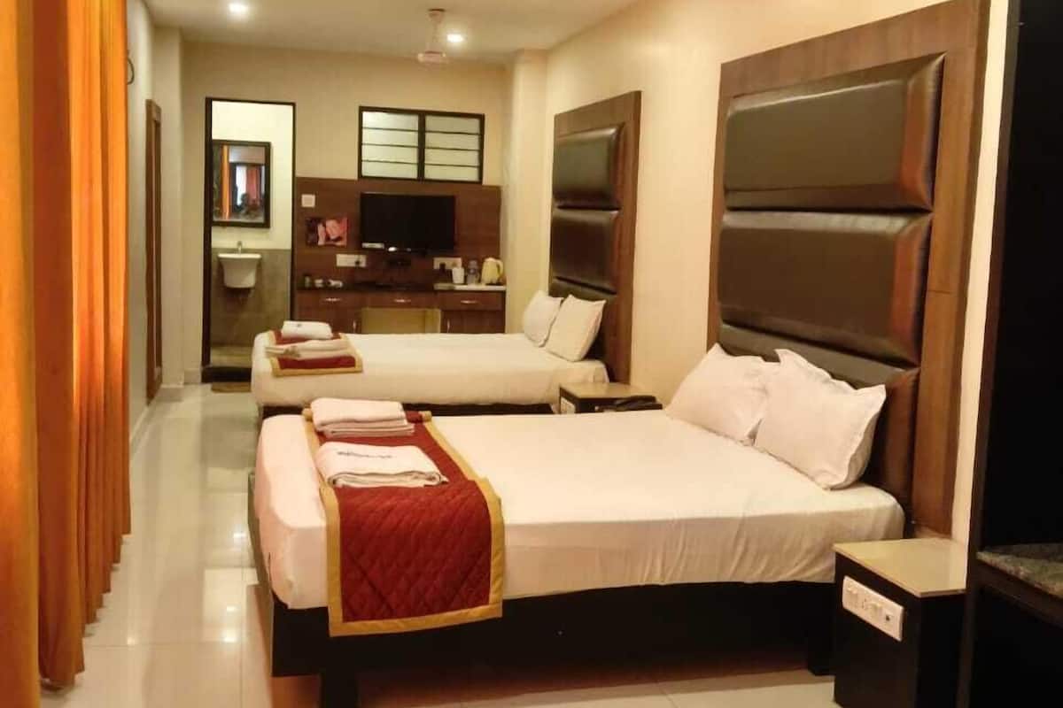 Ein Hotelzimmer mit zwei Betten, einem Schreibtisch und einem im Hintergrund sichtbaren Badezimmer.
