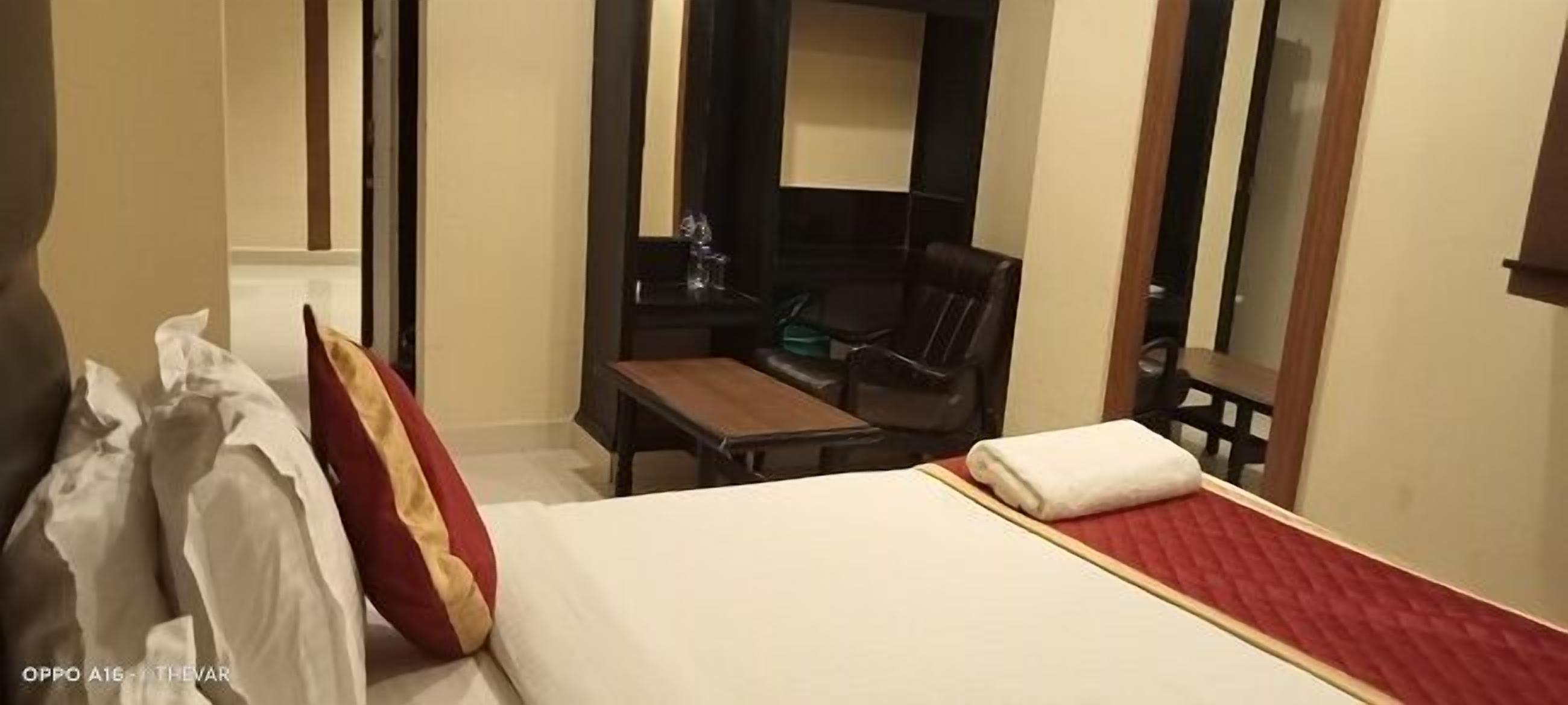A hotel room with a bed, a desk, a chair, and a mirror.