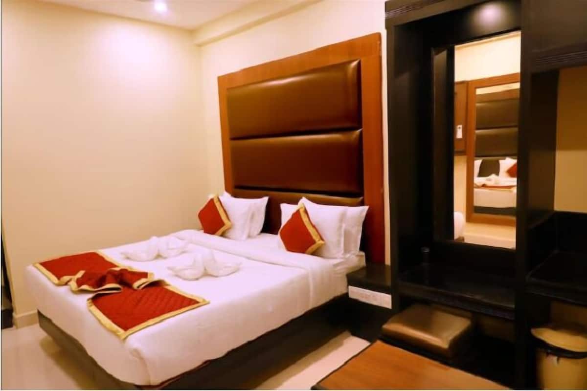 Ein Hotelzimmer mit einem großen Bett, einem hölzernen Kopfteil und einer kleinen Badeinheit.