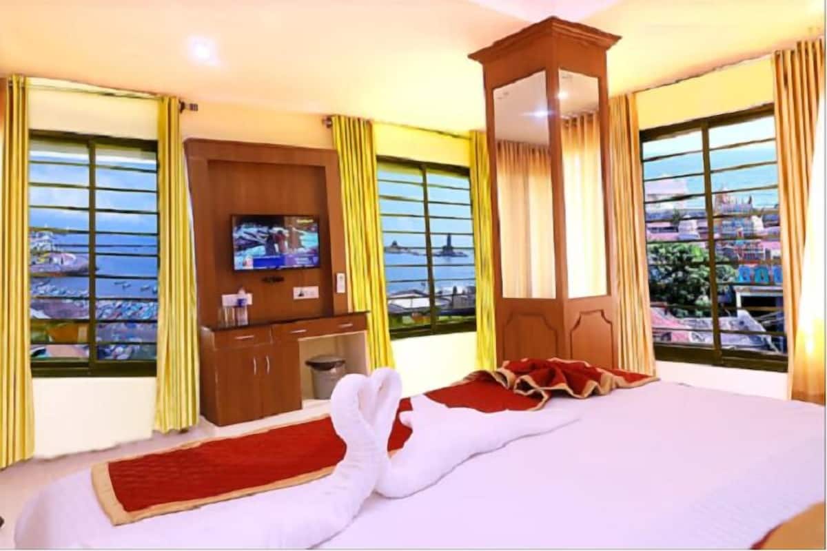 Ein Hotelzimmer mit Bett, Fernseher, Holzschrank und Meerblick.