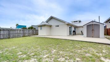 A single-story house with a flat roof and attached garage, set amidst a well-maintained lawn and surrounded by a fence.