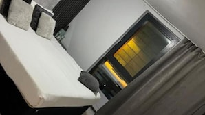 A modern bedroom with a bed, a window with curtains, and a visible light fixture.