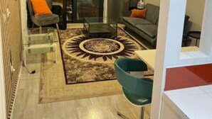 A compact living space with a sofa, a chair, a coffee table, and a patterned rug.