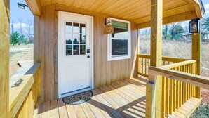 Une véranda en bois avec une porte blanche, un paillasson et une petite fenêtre.