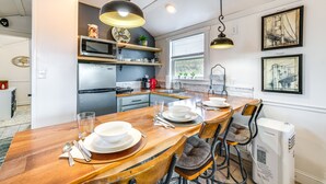 Une cuisine moderne avec une table à manger en bois, préparée pour quatre personnes, un four à micro-ondes et un réfrigérateur.