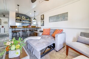 A modern living room with a grey sofa, orange patterned pillows, and a floral centerpiece. - Cozy Decatur Cabin w/ Views ~ 1 Mi to Riverfront! (Decatur)