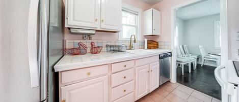 Una cocina con armarios blancos, un refrigerador de acero inoxidable y salpicadero de azulejos.