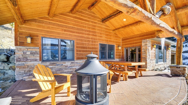 A log cabin with a stone fireplace, wooden deck, and outdoor seating area. - Remote Mountainside Cabin By Stillwater River (Nye)