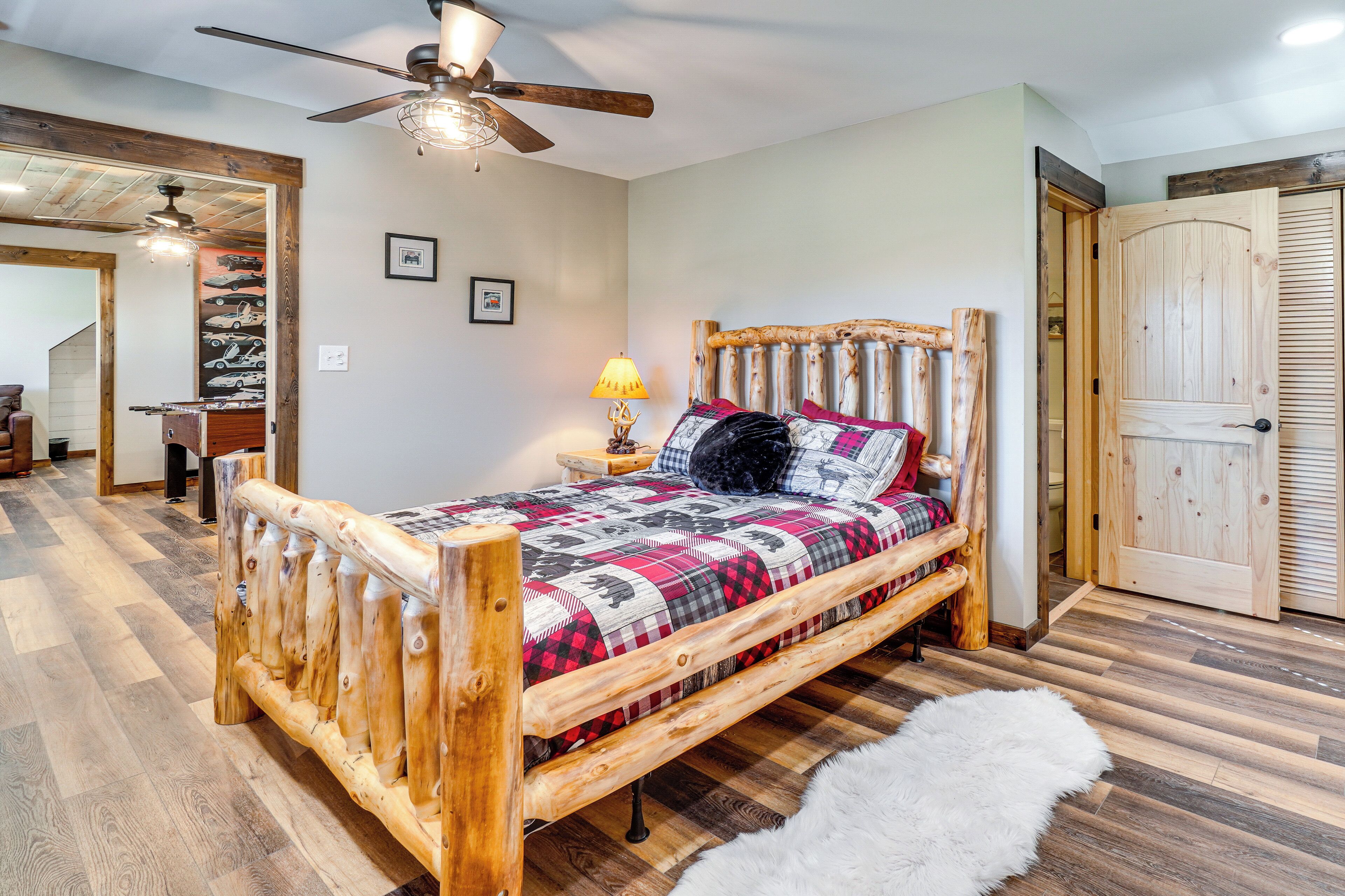 A wooden bed with a quilt, a ceiling fan, a lamp, and a white furry rug.
