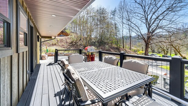 Eine Terrasse mit Tisch und Stühlen, die auf einen bewaldeten Bereich mit Blick auf Hügel blickt.
