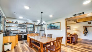 Eine Küche mit Holzausstattung, Edelstahlgeräten und einem Essbereich mit Holztisch und -stühlen.