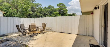 Un espace patio agrémenté d’une clôture blanche, de mobilier d’extérieur et d’une porte située sur le côté droit.