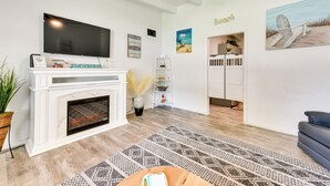 A living room with a fireplace, a flat-screen TV, and beach-themed decorations. - Cozy Fort Walton Beach Escape w/ Private Patio! (Fort Walton Beach)