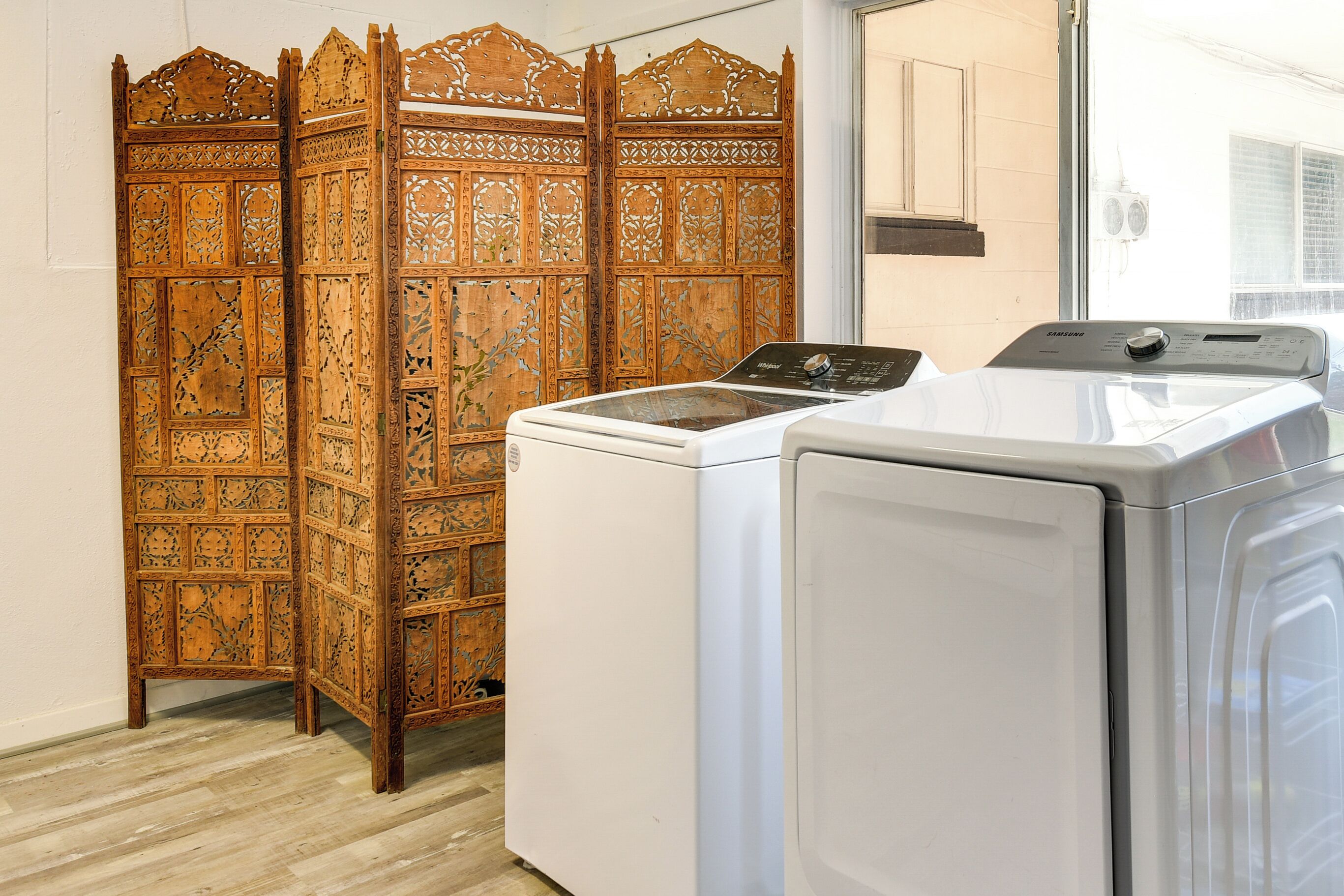 A laundry room with a wooden partition and two white washing machines.