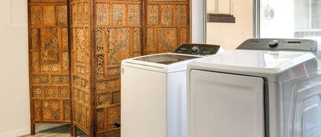 A laundry room with a wooden partition and two white washing machines.