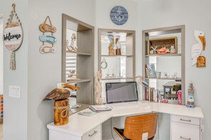 A desk with a computer, a chair, and a shelf with decorative items. - Pet-friendly Fort Pierce Home w/ Pool & Kayaks! (Fort Pierce)