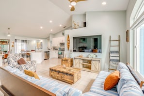 A spacious living area with a sofa, coffee table, and a kitchen in the background. - Pet-friendly Fort Pierce Home w/ Pool & Kayaks! (Fort Pierce)