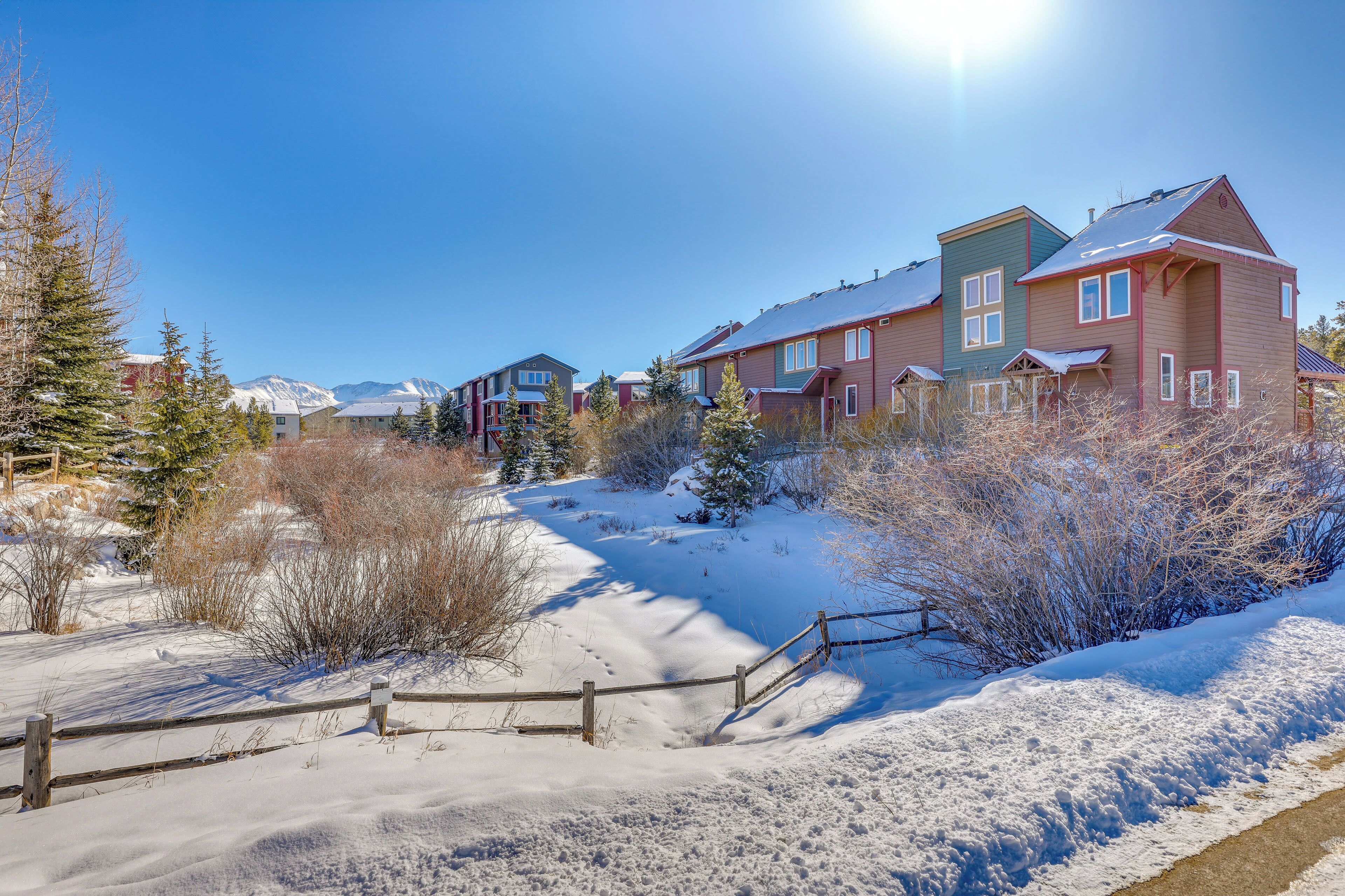 Un barrio residencial con casas, una valla de madera y suelo cubierto de nieve.