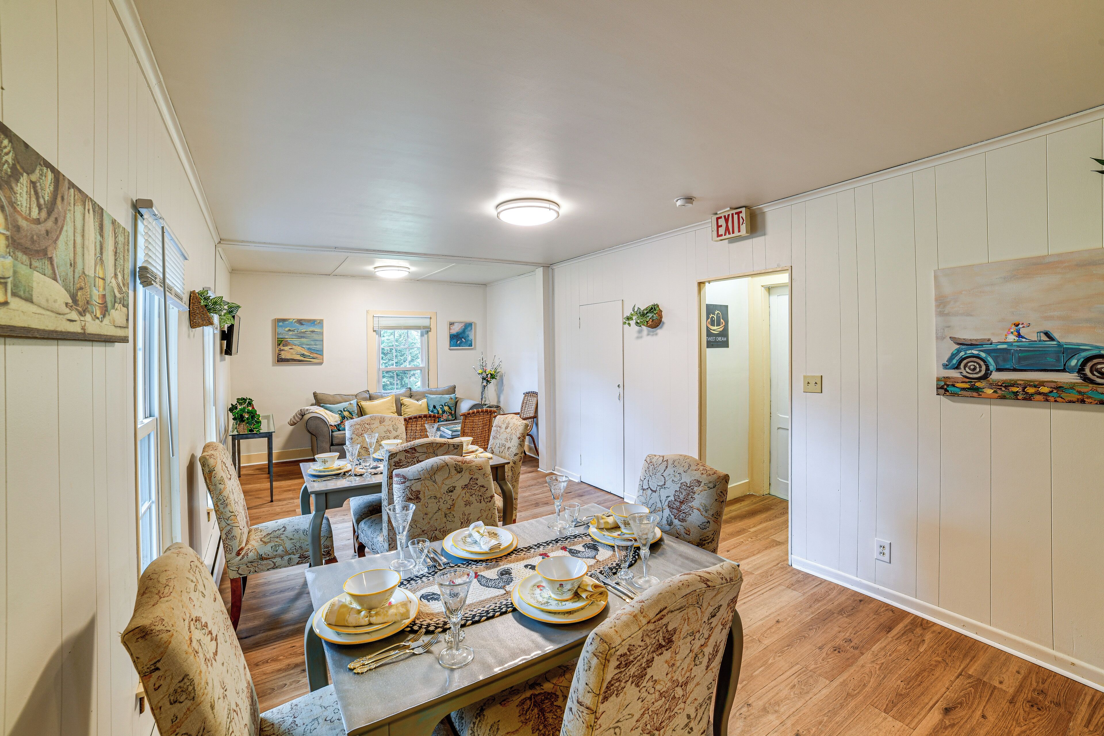 A dining area with a wooden table set for a meal, surrounded by patterned chairs.