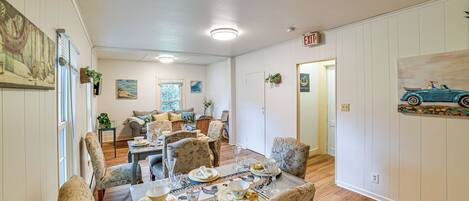 A dining area with a wooden table set for a meal, surrounded by patterned chairs.