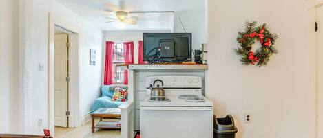 Una cocina pequeña con estufa, ventilador de techo y una ventana.