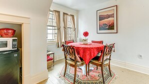 A dining area with a table set for four, a red tablecloth, and a patterned rug. - Cozy Niagara Falls Cottage w/ Gas Grill + Patio! (Niagara Falls)