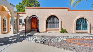 A building with a beige facade, arched windows, and a red door. - Charming Green Valley Townhome w/ Community Pool! (Green Valley)