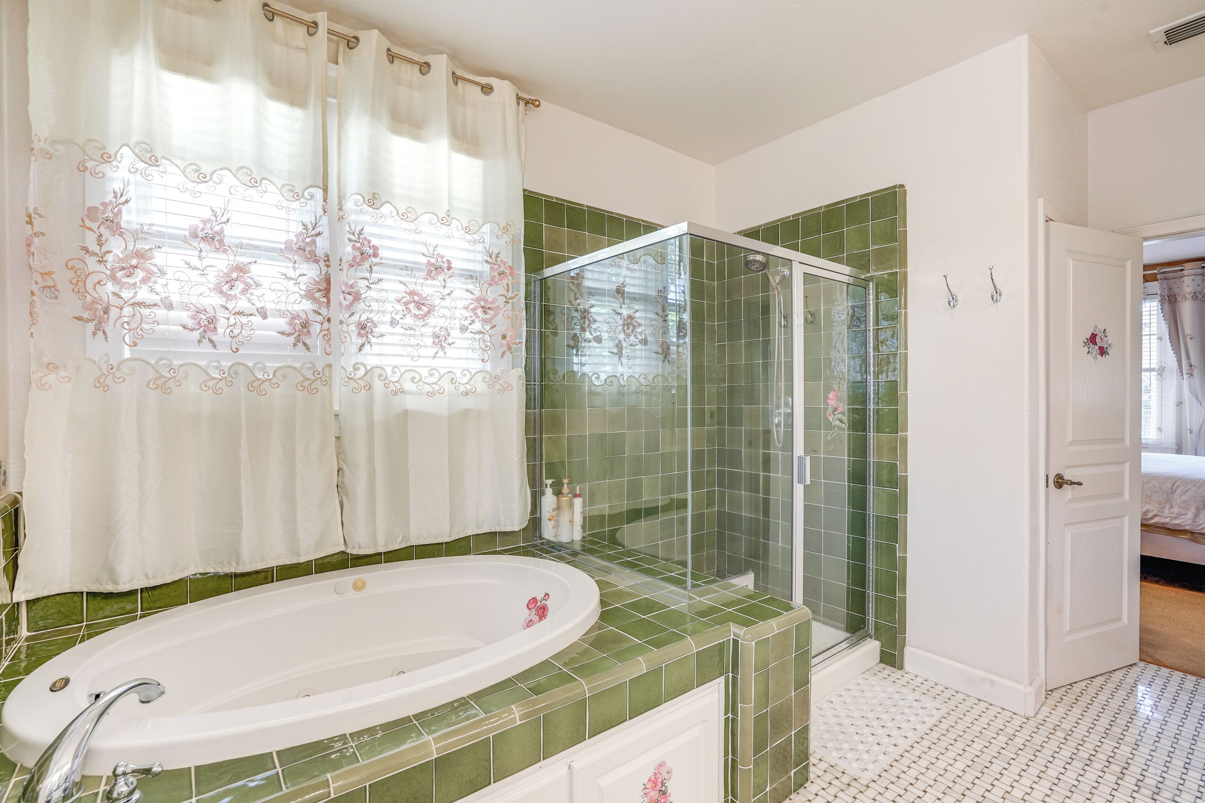A bathroom with a freestanding bathtub, a glass-enclosed shower, and green tiled walls.