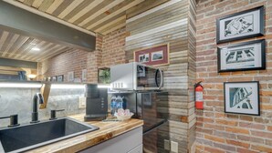 A kitchen with a wooden countertop, a sink, a microwave, and a refrigerator. There are framed pictures on the wall and a fire extinguisher. - Historic Texarkana Studio Rental: Walk to Downtown (Texarkana)
