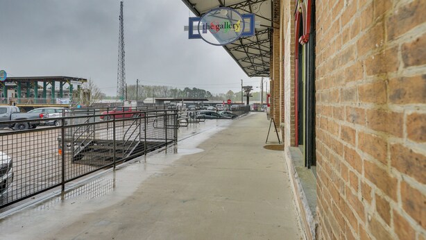 A parking lot with a covered walkway leading to a brick building. - Historic Texarkana Studio Rental: Walk to Downtown (Texarkana)