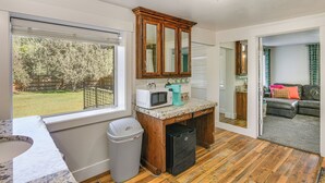 Una cocina con un armario de madera, un microondas y un cubo de basura.